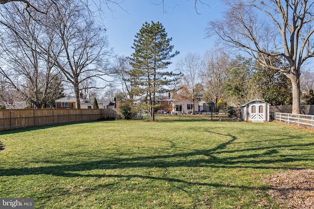 view of yard featuring a storage shed, a fenced backyard, and an outdoor structure