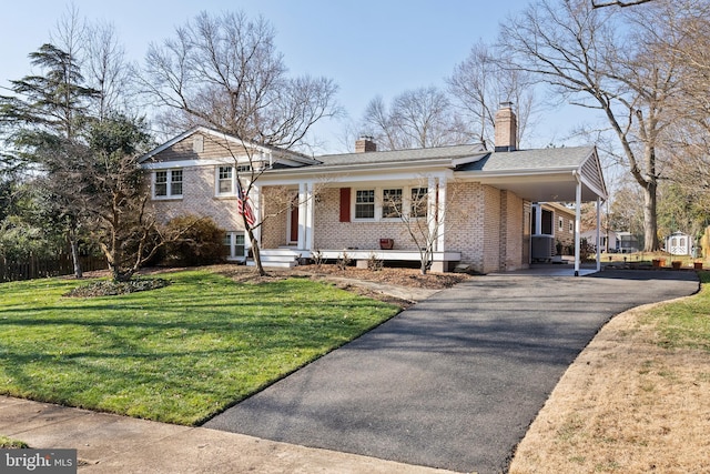 split level home featuring brick siding, aphalt driveway, a front yard, a chimney, and a carport