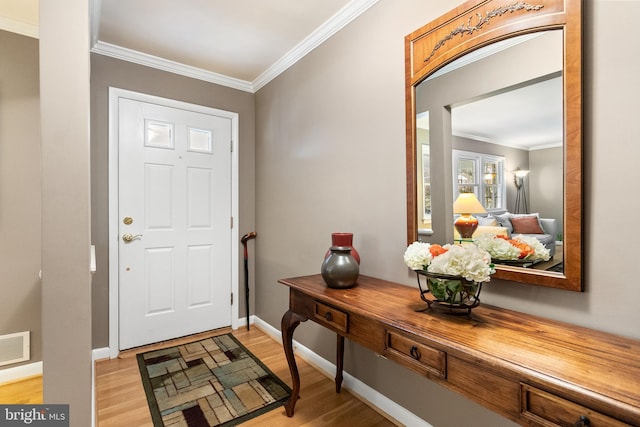 foyer with crown molding, light wood finished floors, and visible vents