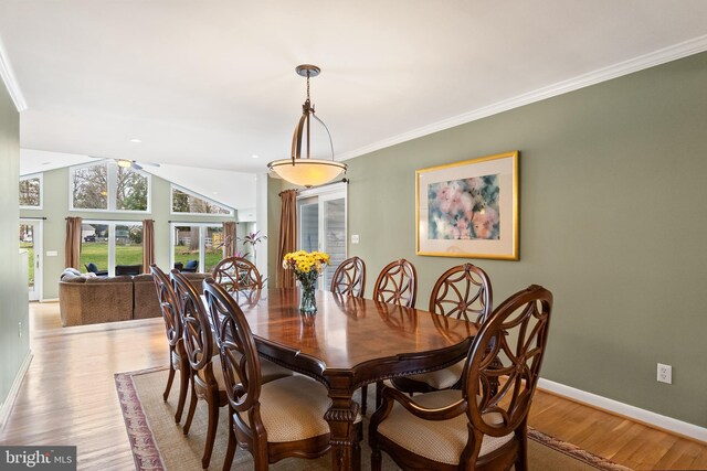 dining room featuring crown molding, light wood finished floors, lofted ceiling, baseboards, and ceiling fan