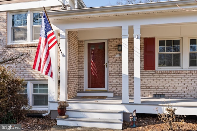 entrance to property featuring crawl space and brick siding