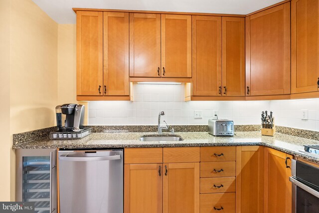 kitchen with stone counters, a sink, appliances with stainless steel finishes, beverage cooler, and decorative backsplash