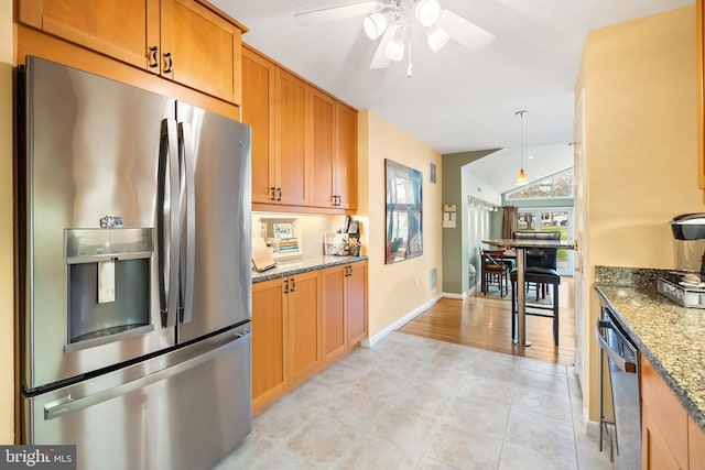 kitchen featuring vaulted ceiling, light stone counters, a ceiling fan, stainless steel fridge, and dishwasher