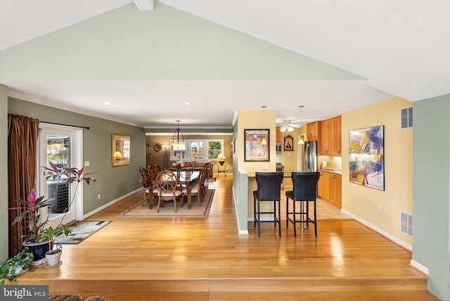 dining space with baseboards, ornamental molding, visible vents, and light wood finished floors