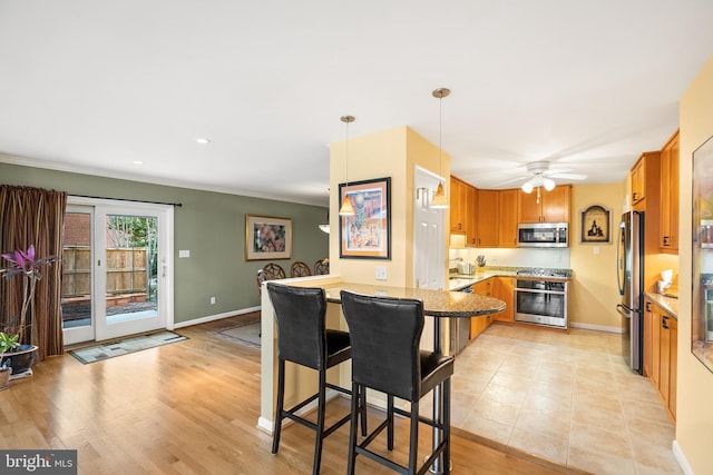 kitchen with light wood-style flooring, baseboards, a peninsula, and stainless steel appliances