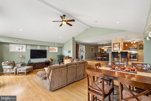 living room featuring light wood finished floors, vaulted ceiling with beams, visible vents, and a ceiling fan