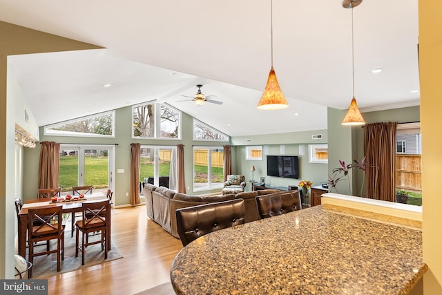 kitchen with stone counters, a ceiling fan, light wood-style flooring, visible vents, and decorative light fixtures