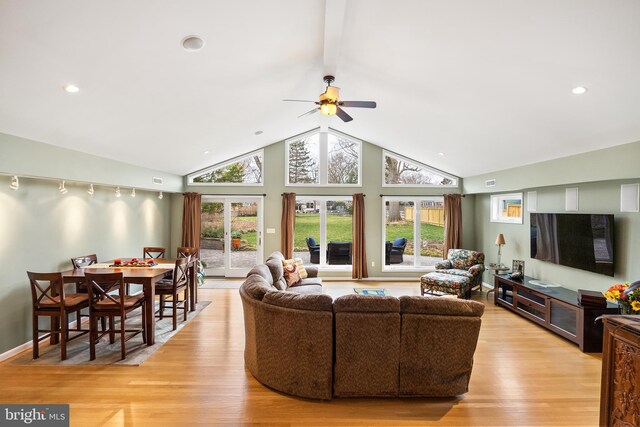 living area featuring high vaulted ceiling, baseboards, light wood finished floors, visible vents, and a ceiling fan