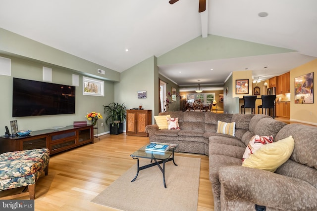 living area with baseboards, light wood-style floors, beamed ceiling, visible vents, and a ceiling fan