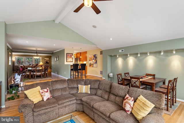 living room with vaulted ceiling with beams, light wood-style floors, ceiling fan, and baseboards