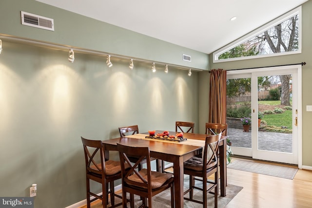 dining space with baseboards, lofted ceiling, light wood-style flooring, and visible vents
