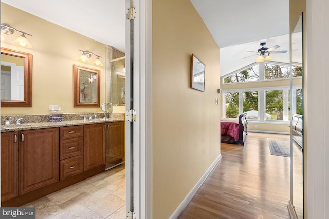 full bathroom featuring a sink, a ceiling fan, lofted ceiling, baseboards, and double vanity