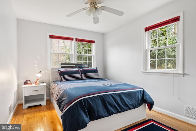 bedroom with baseboards, visible vents, wood finished floors, and ceiling fan