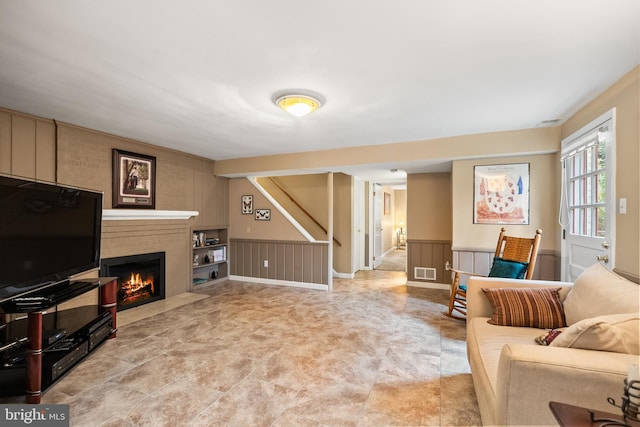 living room with a fireplace, visible vents, and wainscoting