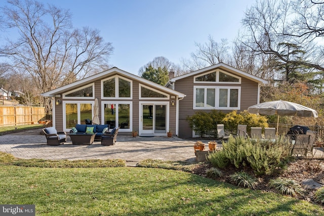 rear view of property featuring an outdoor living space, fence, a chimney, a yard, and a patio area