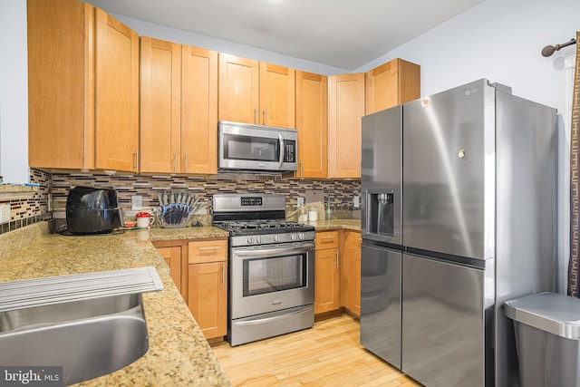 kitchen featuring light countertops, appliances with stainless steel finishes, backsplash, and light wood-style flooring