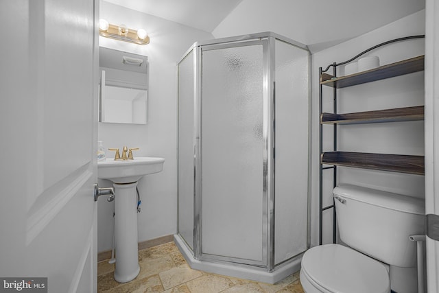 bathroom featuring a sink, toilet, a shower stall, and stone tile floors