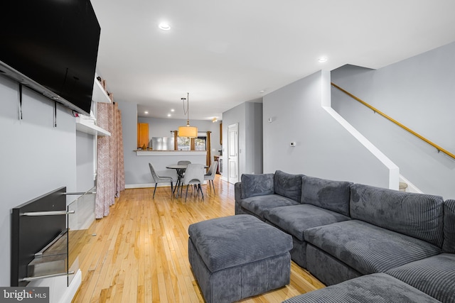 living room featuring light wood-type flooring, stairway, baseboards, and recessed lighting