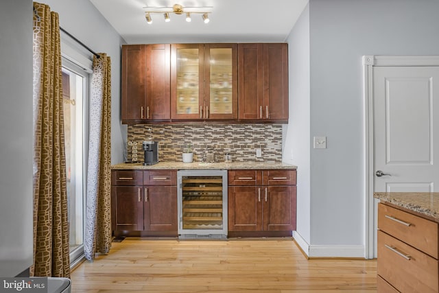 bar featuring tasteful backsplash, beverage cooler, baseboards, and light wood-style flooring