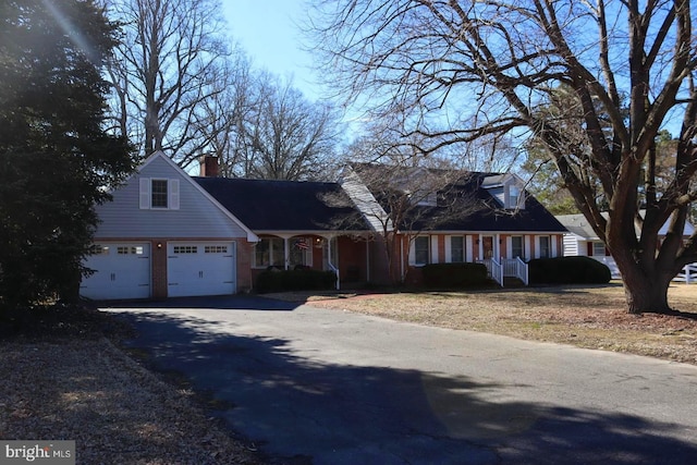 cape cod-style house featuring aphalt driveway, a chimney, and an attached garage