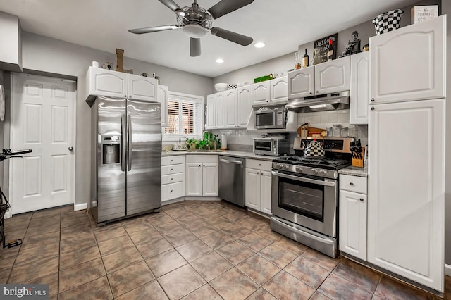 kitchen featuring appliances with stainless steel finishes, white cabinetry, under cabinet range hood, and tasteful backsplash