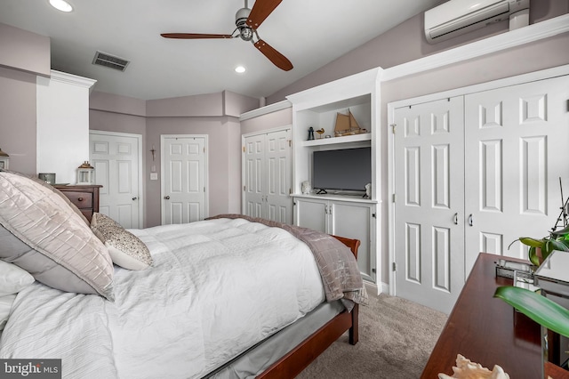 carpeted bedroom with a wall unit AC, recessed lighting, visible vents, multiple closets, and vaulted ceiling