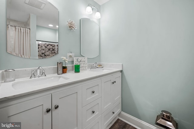 full bath with visible vents, a sink, baseboards, and double vanity