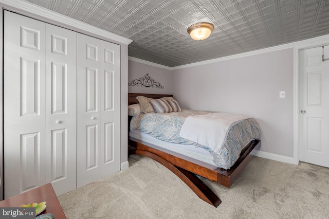 carpeted bedroom with ornamental molding, a closet, an ornate ceiling, and baseboards