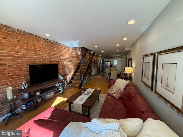 living room featuring stairs, brick wall, wood finished floors, and recessed lighting