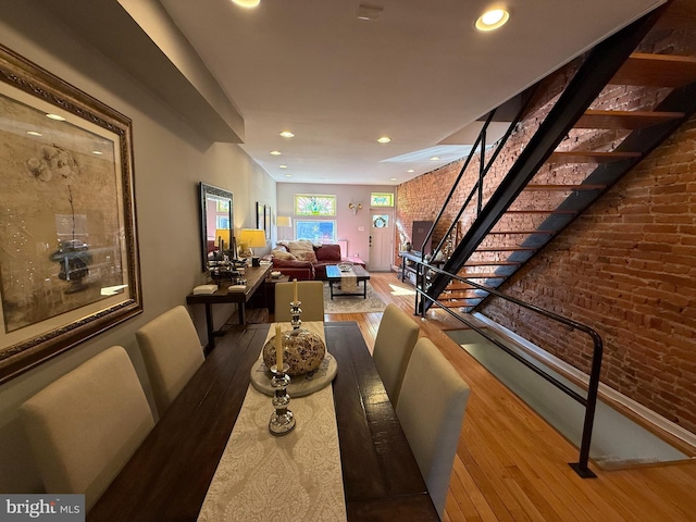 dining area with hardwood / wood-style flooring, brick wall, stairs, and recessed lighting