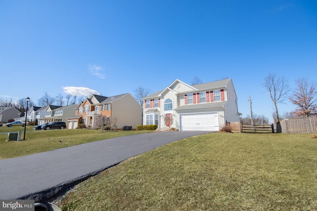 traditional-style home with a garage, fence, driveway, a residential view, and a front yard