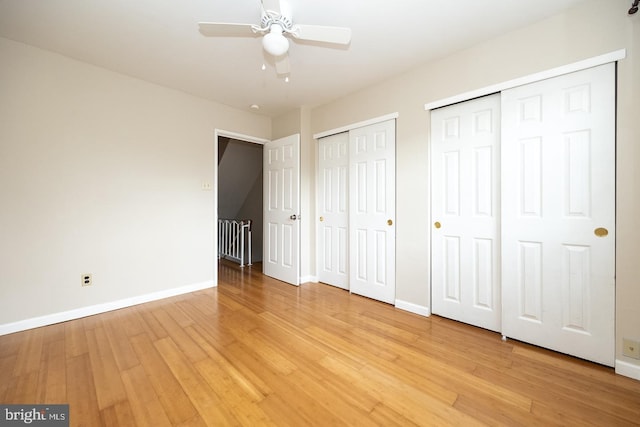 unfurnished bedroom with baseboards, ceiling fan, two closets, and light wood-style floors