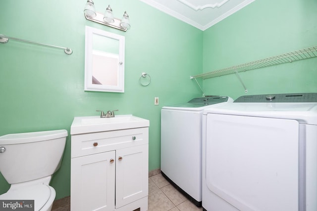 clothes washing area featuring light tile patterned flooring, laundry area, a sink, washing machine and clothes dryer, and crown molding