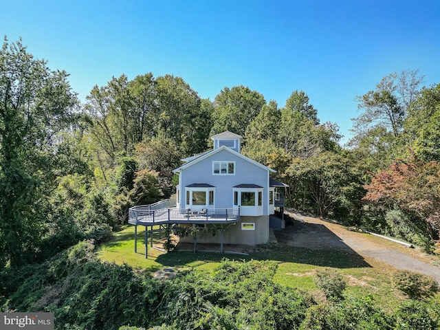 5112 Shore Dr, Huntingtown, MD 20639 - rear view of house with a deck, a forest view, and a yard