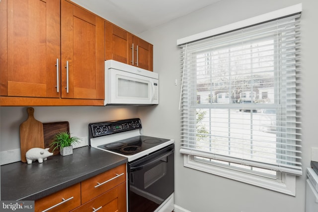 kitchen with white microwave, plenty of natural light, range with electric cooktop, and brown cabinets