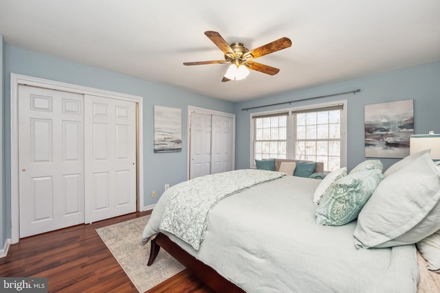 bedroom with a ceiling fan, wood finished floors, baseboards, and two closets