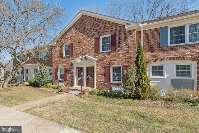 view of front facade with brick siding and a front lawn