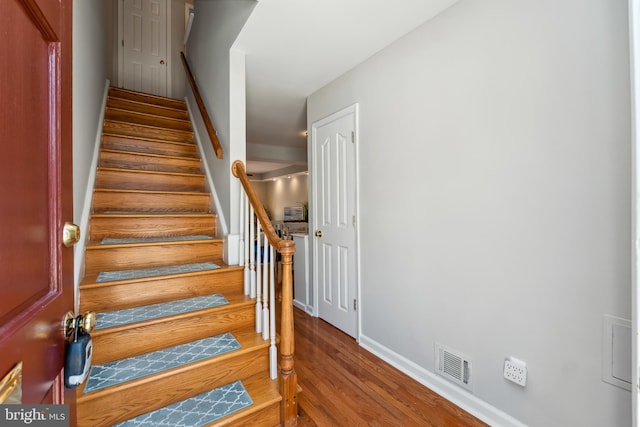 stairway with wood finished floors, visible vents, and baseboards