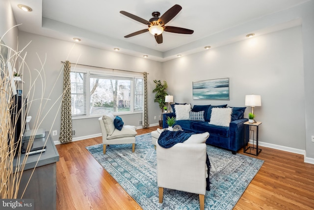 living area with wood finished floors, a ceiling fan, and baseboards