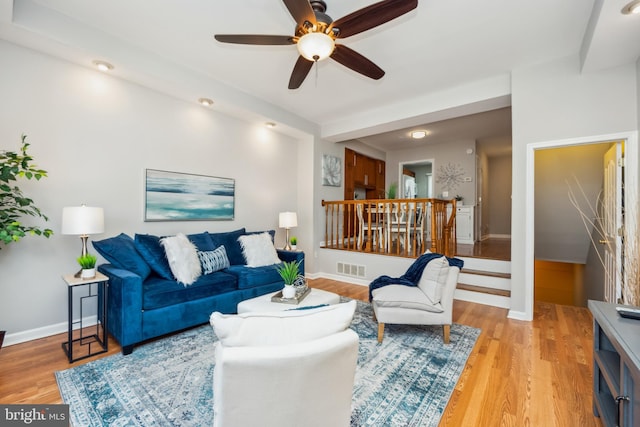 living room with visible vents, light wood-style flooring, and baseboards