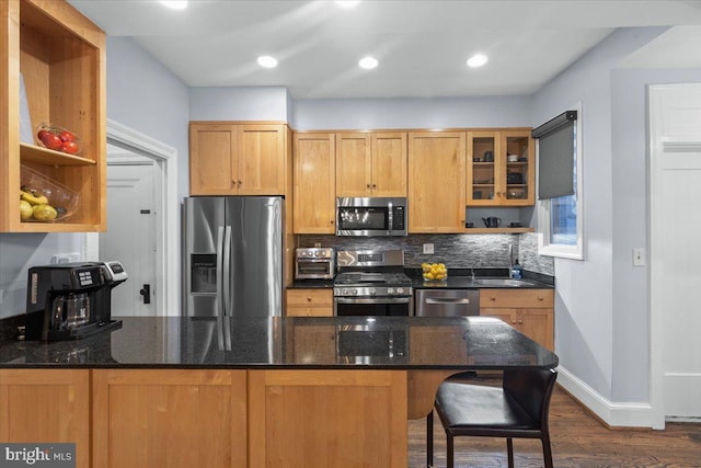 2652 Woodley Pl NW, Washington, DC 20008 - kitchen featuring appliances with stainless steel finishes, a sink, decorative backsplash, dark wood finished floors, and a peninsula
