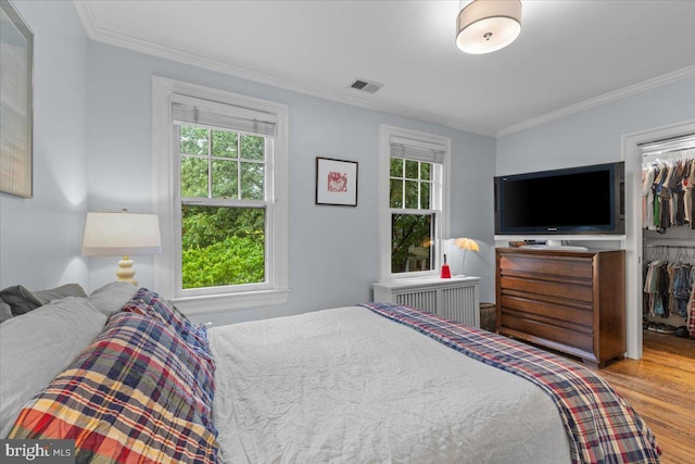 2652 Woodley Pl NW, Washington, DC 20008 - bedroom featuring radiator heating unit, ornamental molding, a spacious closet, wood finished floors, and a closet