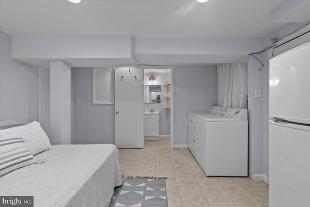 2652 Woodley Pl NW, Washington, DC 20008 - bedroom with freestanding refrigerator, separate washer and dryer, light tile patterned floors, ensuite bath, and baseboards