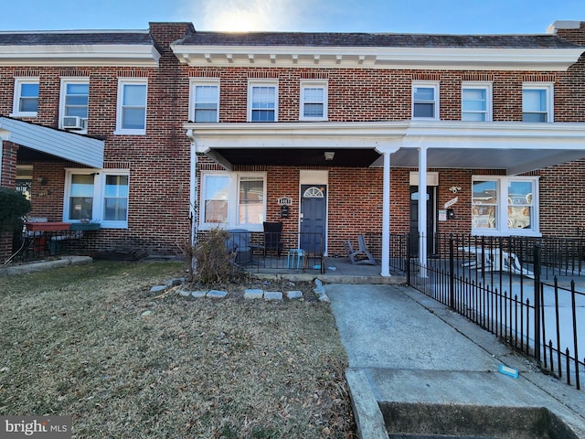 view of property with brick siding, a porch, and cooling unit