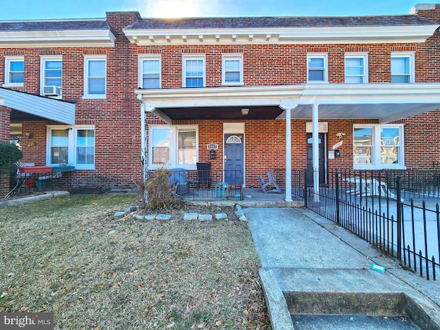 multi unit property featuring covered porch, cooling unit, and brick siding