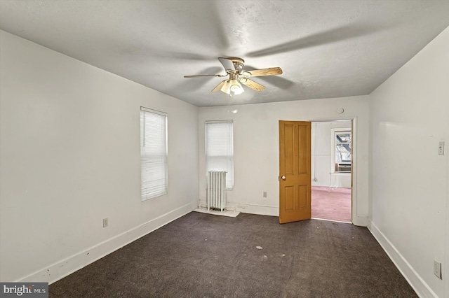 interior space with radiator, ceiling fan, baseboards, and dark colored carpet