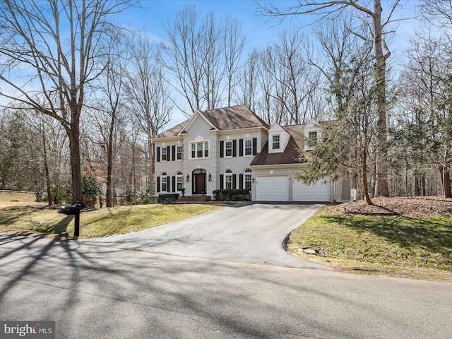 colonial-style house featuring driveway, a front yard, and a garage