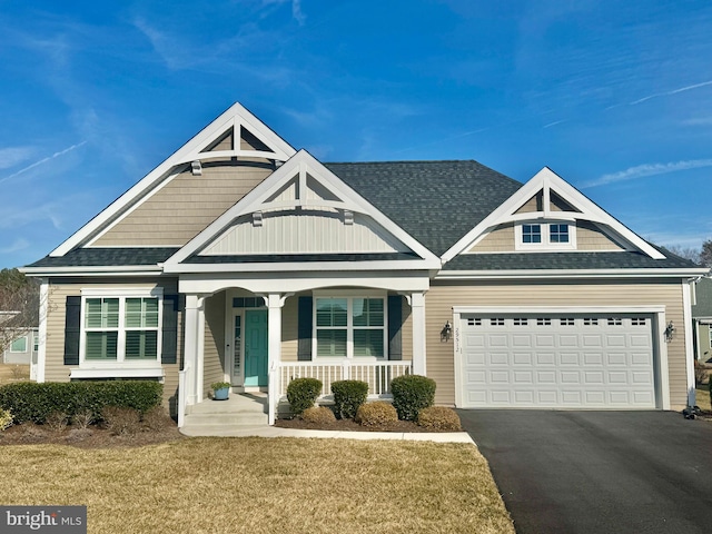 view of front of home featuring roof with shingles, a porch, a garage, driveway, and a front lawn