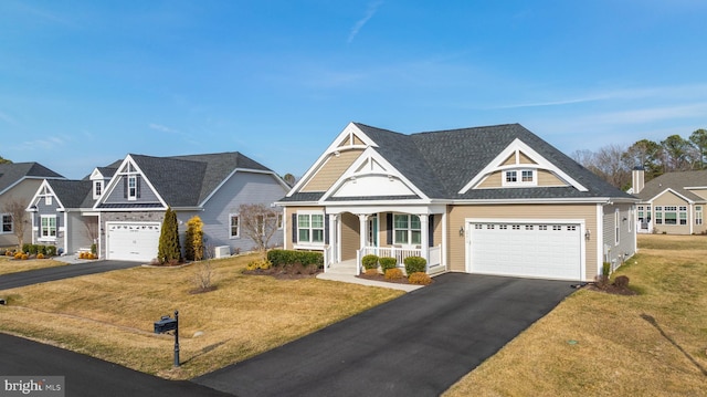 view of front of house with a porch, roof with shingles, driveway, and a front lawn