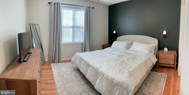 bedroom with light wood-type flooring, multiple windows, and baseboards